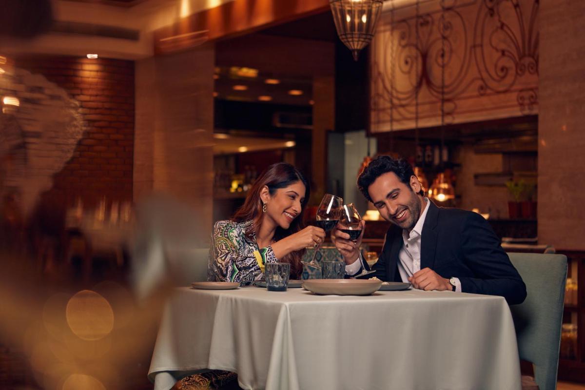 a man and woman sitting at a table drinking wine at Hyatt Regency Pune Hotel & Residences in Pune