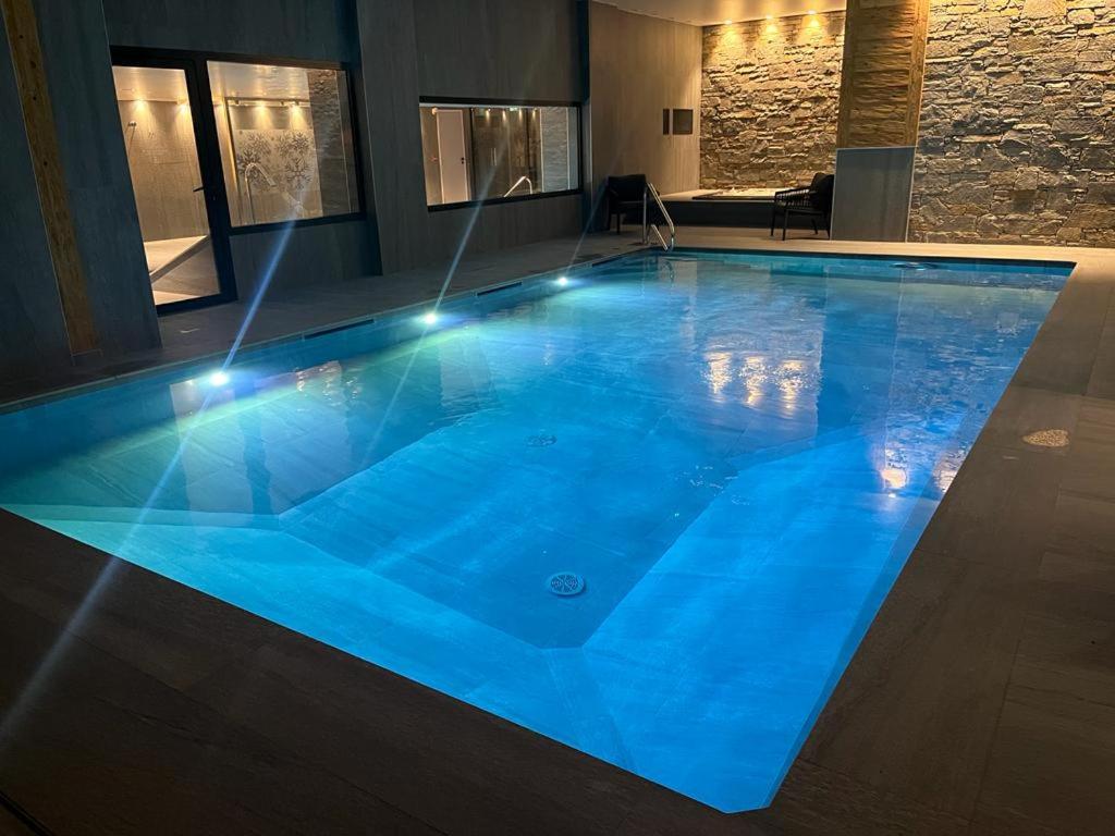 une grande piscine bleue éclairée dans l'établissement Hôtel Alpina & SPA - Restaurant Oxalis, aux Gets