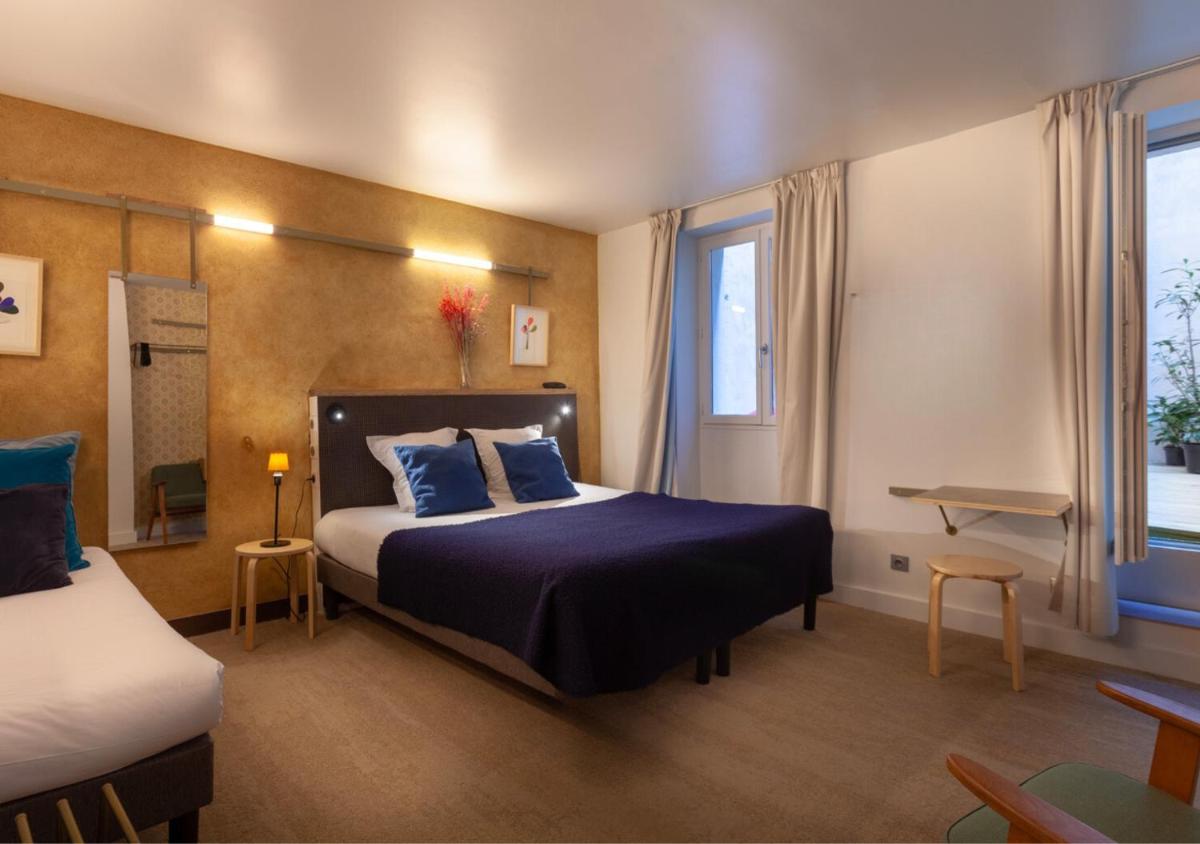 une chambre avec un grand lit aux oreillers bleus dans l'établissement Hôtel La Nouvelle République & Hammam, à Paris