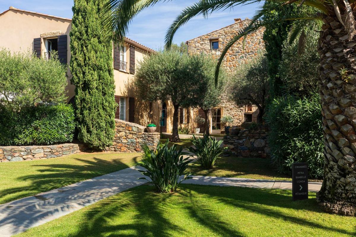 une maison avec un palmier et un jardin dans l'établissement Hôtel La Dimora & Spa, à Saint-Florent