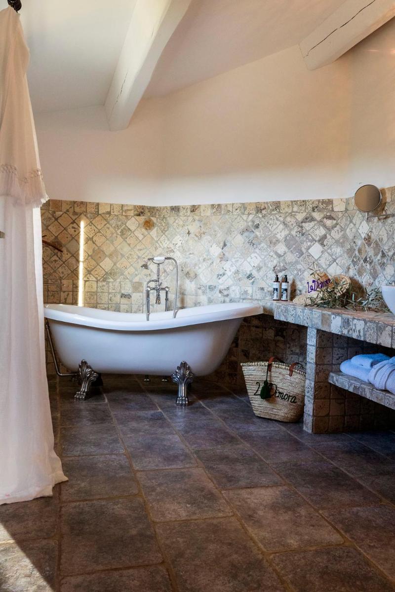 une baignoire dans une salle de bain avec un mur en pierre dans l'établissement Hôtel La Dimora & Spa, à Saint-Florent