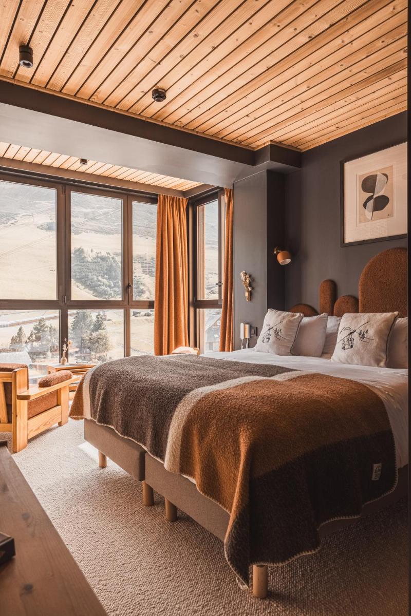 une chambre avec un grand lit avec une grande fenêtre dans l'établissement La Voie Lactée, à La Mongie