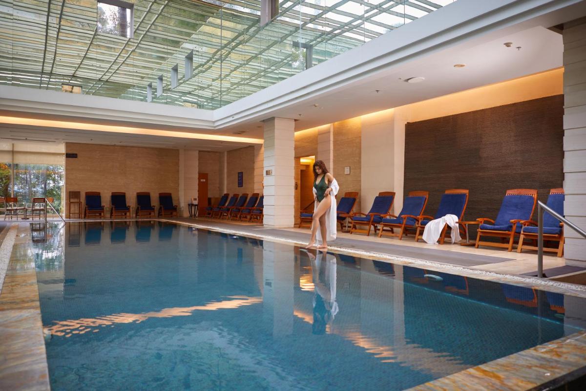 a woman is standing next to a swimming pool at Hyatt Regency Pune Hotel & Residences in Pune