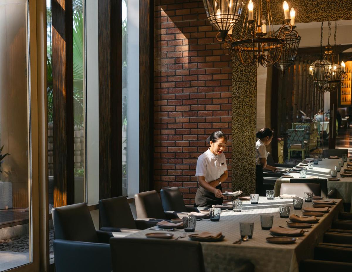 a man standing in a restaurant with tables and chairs at Hyatt Regency Pune Hotel & Residences in Pune