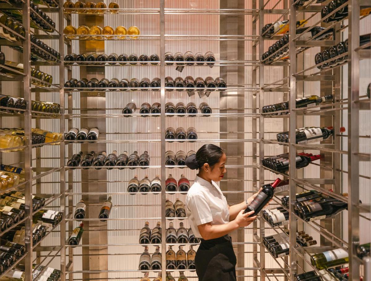 a woman standing in front of a wall of wine bottles at Hyatt Regency Pune Hotel & Residences in Pune
