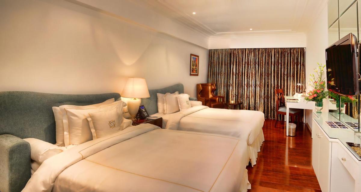 a hotel room with two beds and a television at La Marvella, Bengaluru in Bengaluru