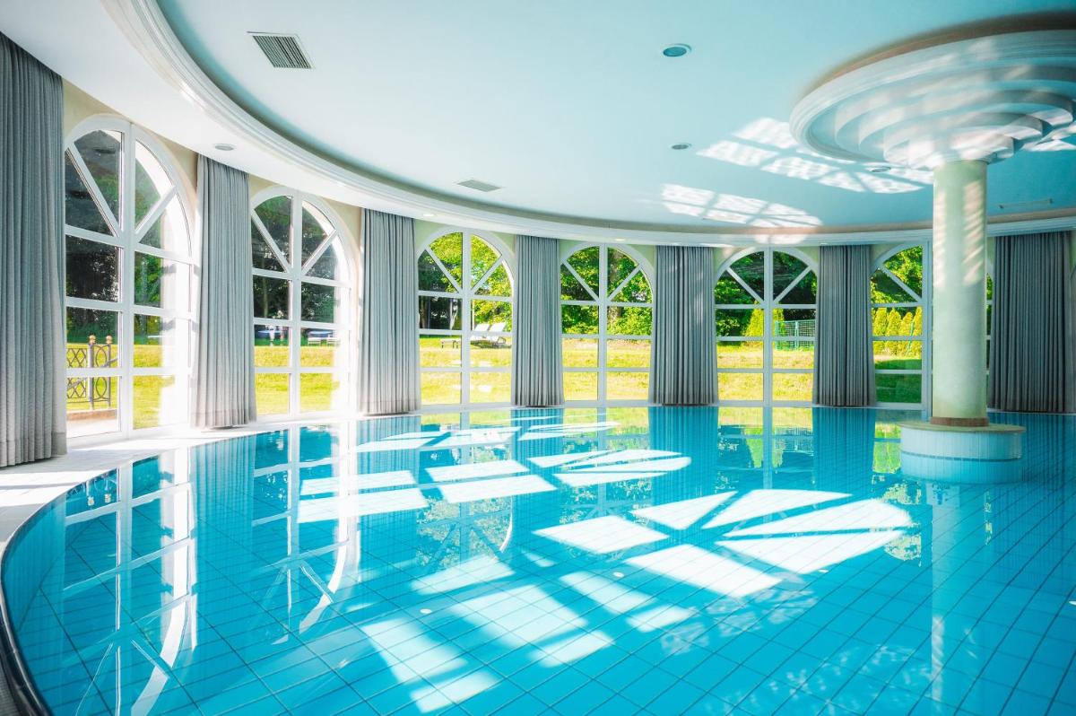 ein großer Swimmingpool mit blauen Fliesenböden und Fenstern in der Unterkunft Steigenberger Hotel Der Sonnenhof in Bad Wörishofen
