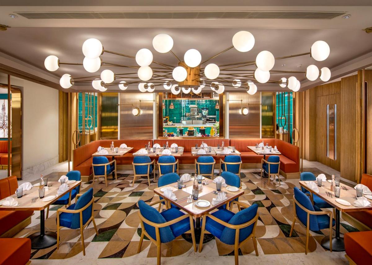 a restaurant with tables and chairs and a chandelier at Welcomhotel by ITC Hotels, Cathedral Road, Chennai in Chennai