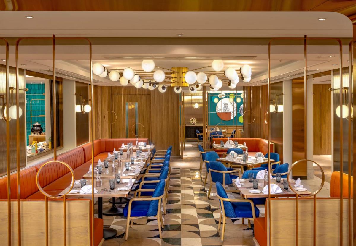 a dining room with tables and blue chairs at Welcomhotel by ITC Hotels, Cathedral Road, Chennai in Chennai
