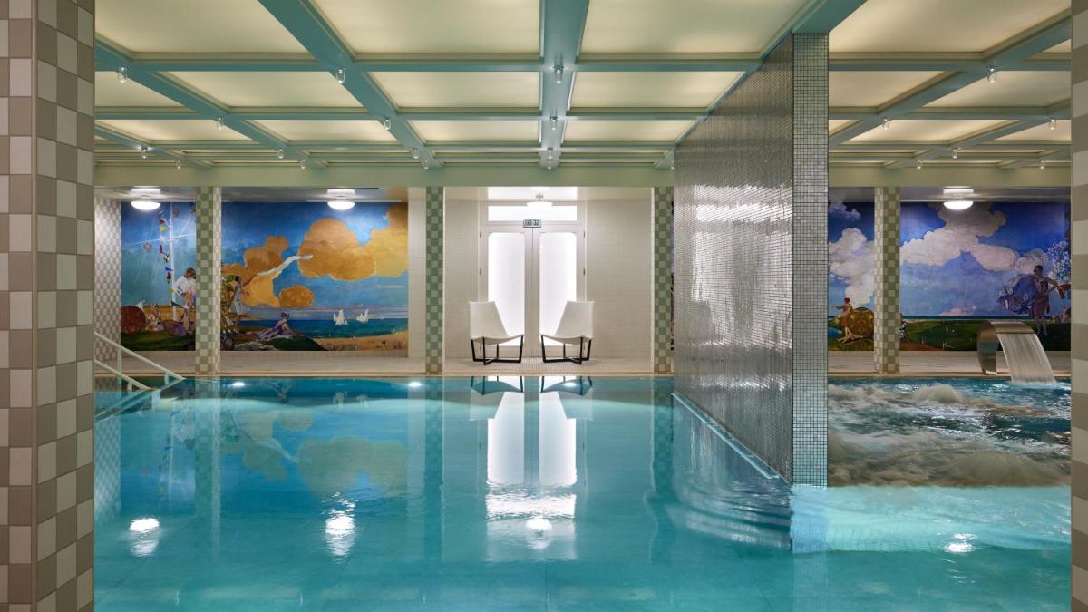 une piscine avec deux chaises longues dans un bâtiment dans l'établissement Cures Marines Hotel Thalasso & Spa Trouville - MGallery Collection, à Trouville-sur-Mer
