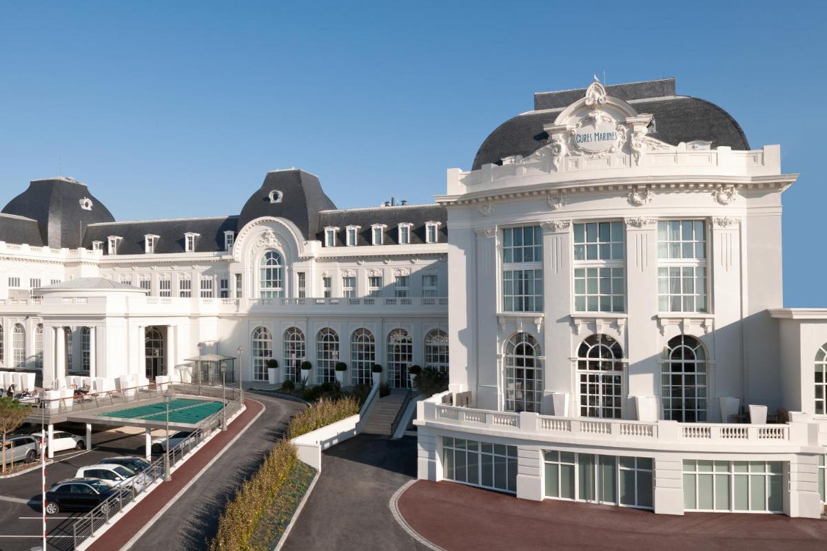un bâtiment blanc avec un court de tennis devant dans l'établissement Cures Marines Hotel Thalasso & Spa Trouville - MGallery Collection, à Trouville-sur-Mer