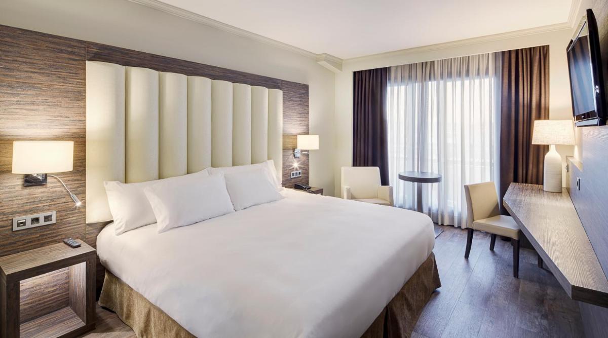 Una gran cama blanca en una habitación de hotel. en Gran Hotel Luna de Granada, en Granada