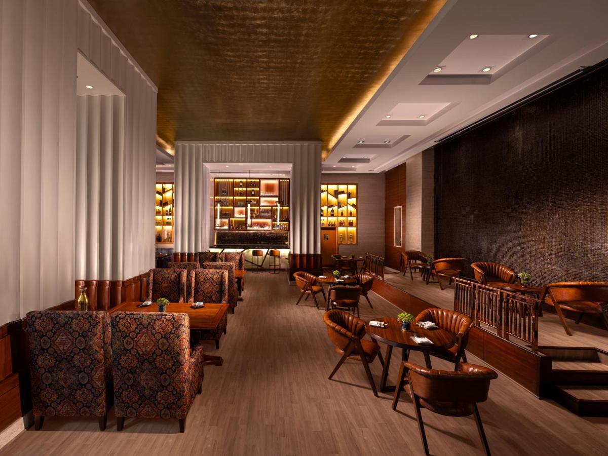 a restaurant with tables and chairs and a bar at Jaypee Vasant Continental in New Delhi