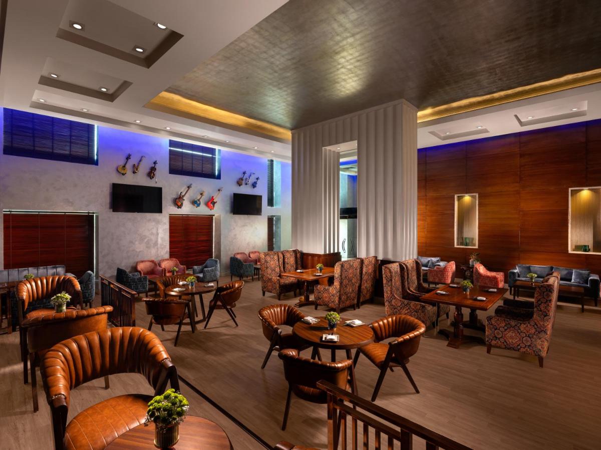 a restaurant with tables and chairs and a lobby at Jaypee Vasant Continental in New Delhi