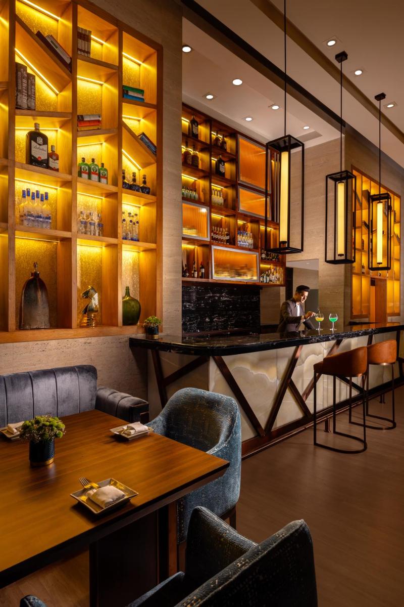 a restaurant with a bar and tables and chairs at Jaypee Vasant Continental in New Delhi