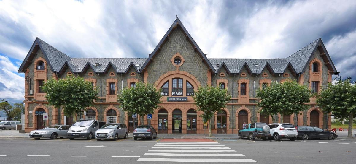 Un gran edificio con coches aparcados en un estacionamiento. en Hotel Parada Puigcerda, en Puigcerdà
