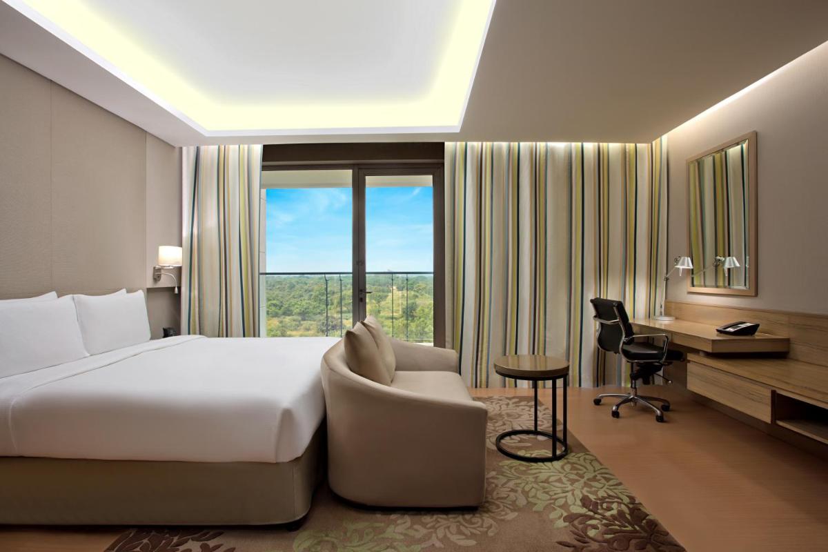 a hotel room with a bed and a desk and a window at DoubleTree Suites by Hilton Bengaluru Outer Ring Road in Bengaluru
