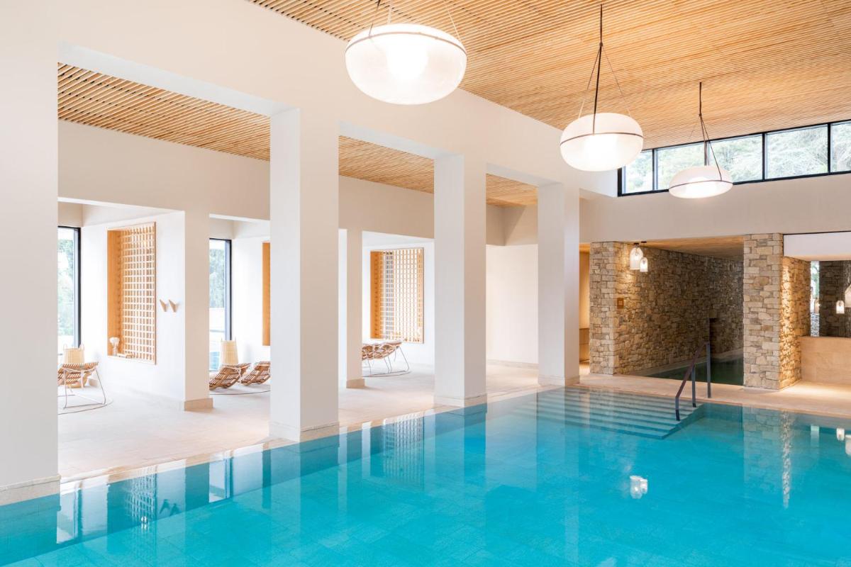 une piscine intérieure d'eau bleue dans un bâtiment dans l'établissement Le Couvent des Minimes, un Hôtel & Spa L'Occitane en Provence, à Mane