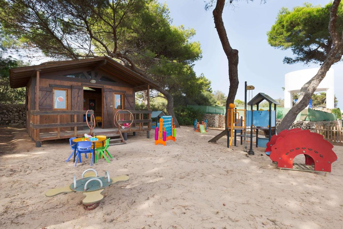 un parque infantil con un pequeño edificio y una zona de juegos en Alua Illa de Menorca, en S'Algar