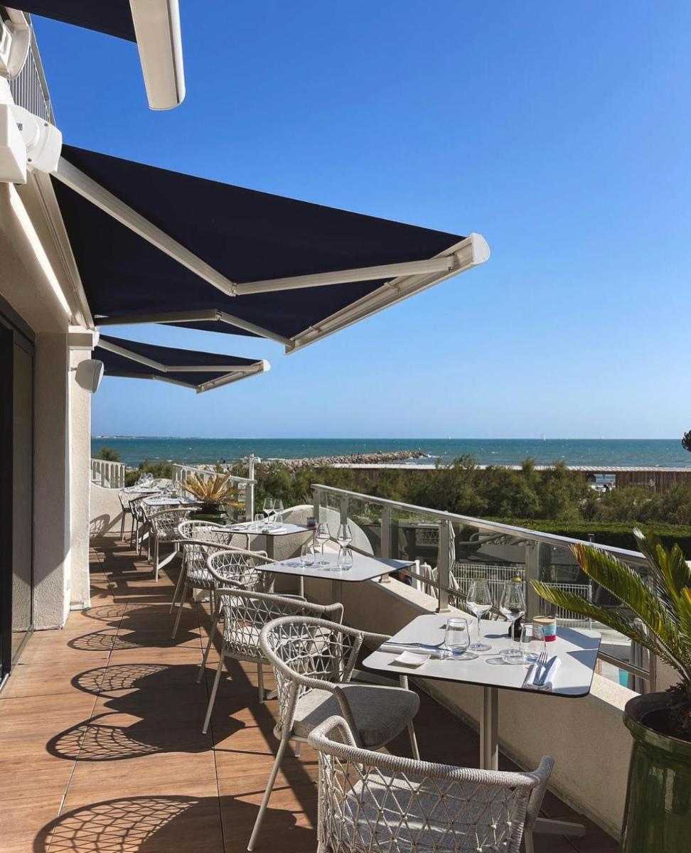 une rangée de tables et de chaises avec vue sur l'océan dans l'établissement Hôtel La Plage 5 étoiles La Grande Motte, à La Grande Motte 37 autres photos