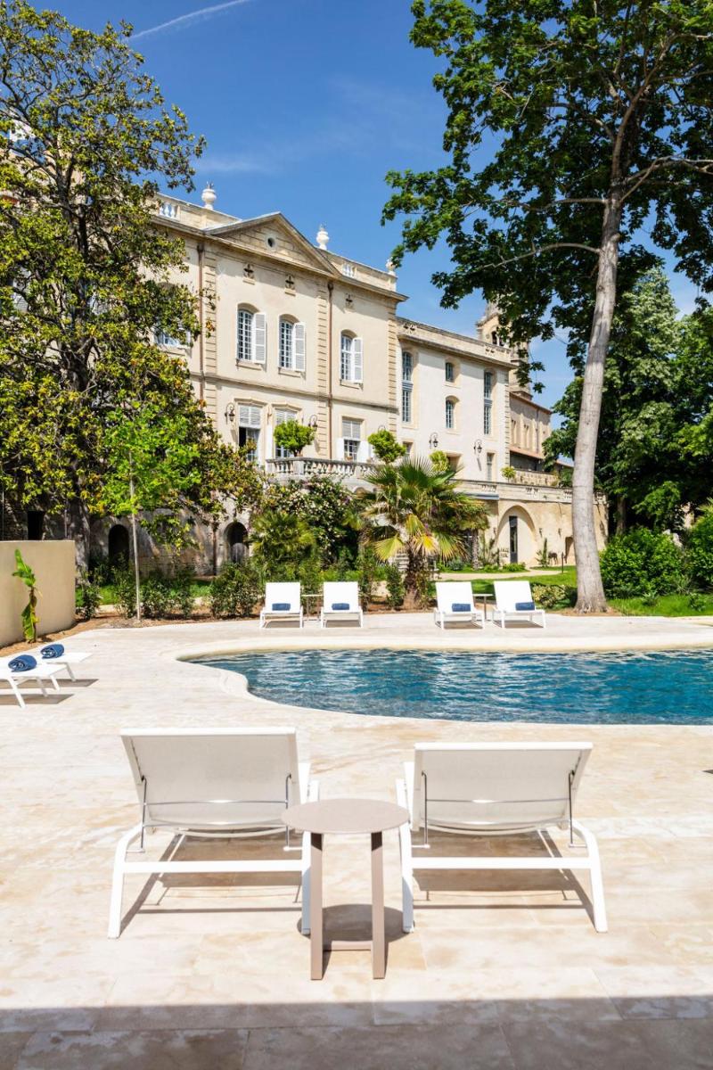 - un groupe de chaises et une piscine en face d'un bâtiment dans l'établissement Château de Collias, à Collias