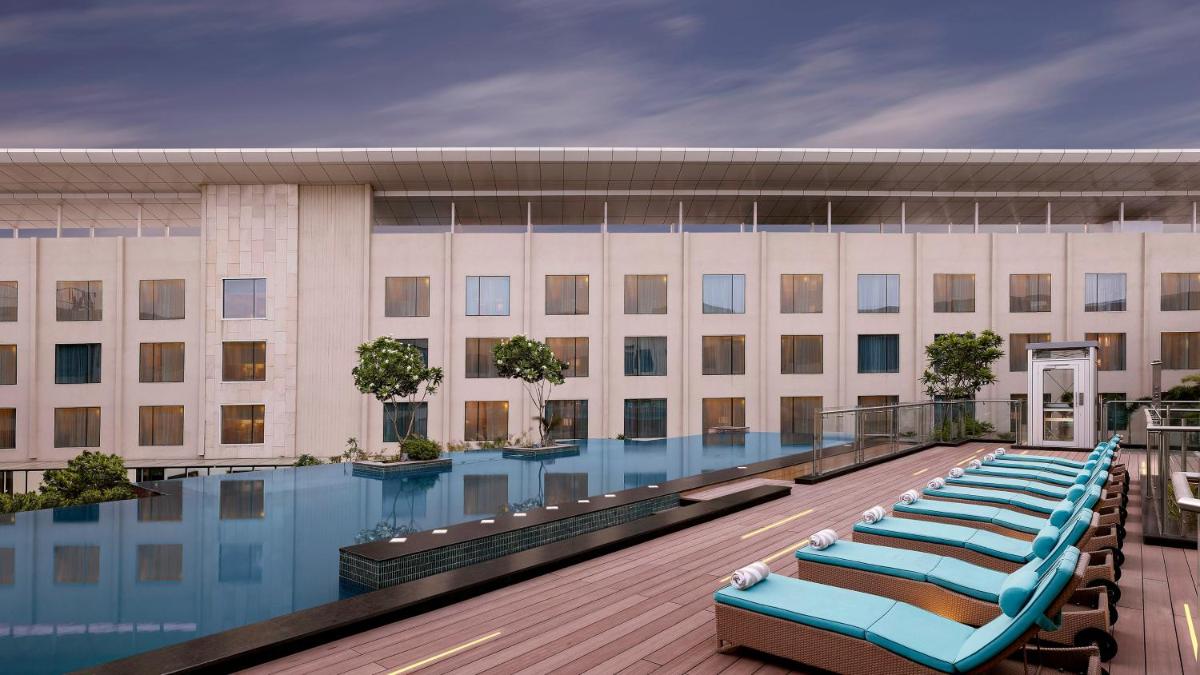 a hotel with a swimming pool with blue lounge chairs at InterContinental Jaipur Tonk Road by IHG in Jaipur