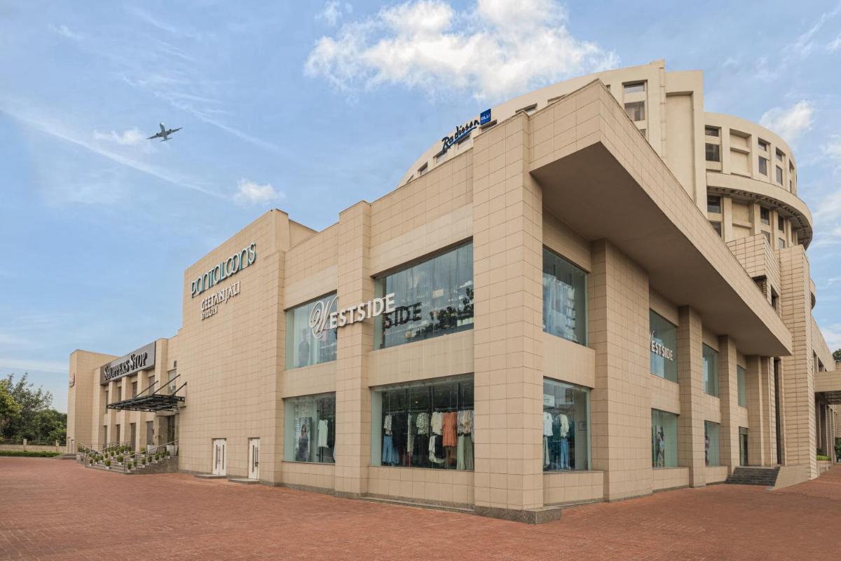 a large building with an airplane flying over it at Radisson Blu Hotel New Delhi Dwarka in New Delhi a large building with an airplane flying over it at Radisson Blu Hotel New Delhi Dwarka in New Delhi