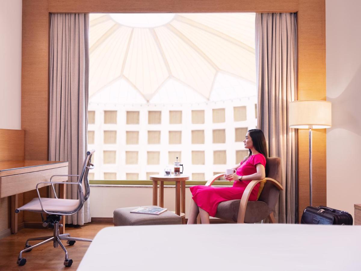 a woman sitting in a chair in front of a window at Radisson Blu Hotel New Delhi Dwarka in New Delhi a woman sitting in a chair in front of a window at Radisson Blu Hotel New Delhi Dwarka in New Delhi