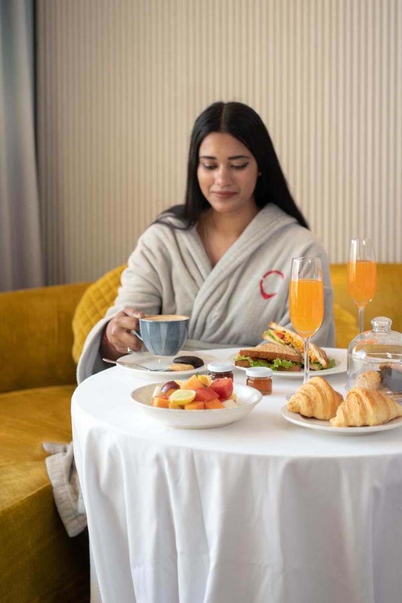 a woman sitting at a table with a plate of food at Hyatt Centric Sector17 Chandigarh in Chandīgarh