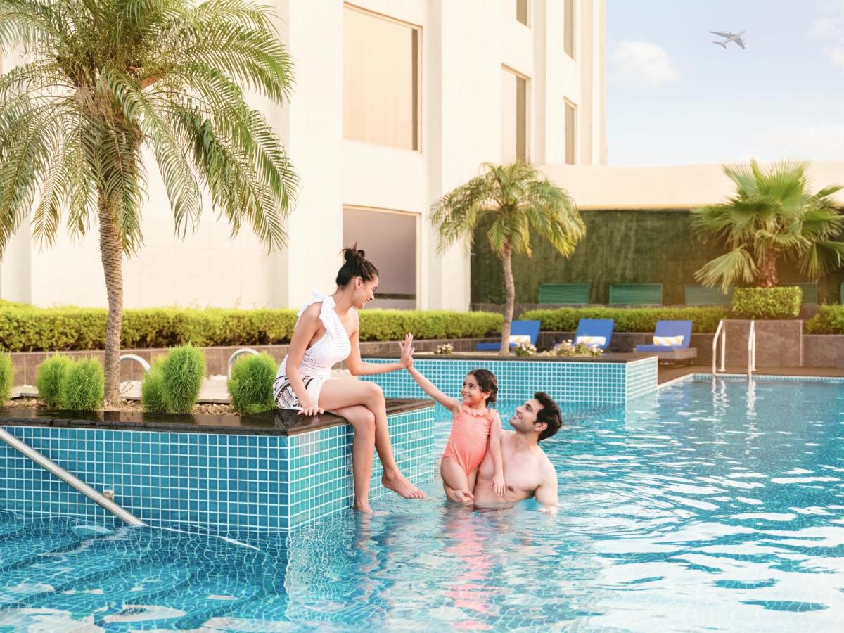 a woman and two girls sitting in a swimming pool at Radisson Blu Hotel New Delhi Dwarka in New Delhi a woman and two girls sitting in a swimming pool at Radisson Blu Hotel New Delhi Dwarka in New Delhi