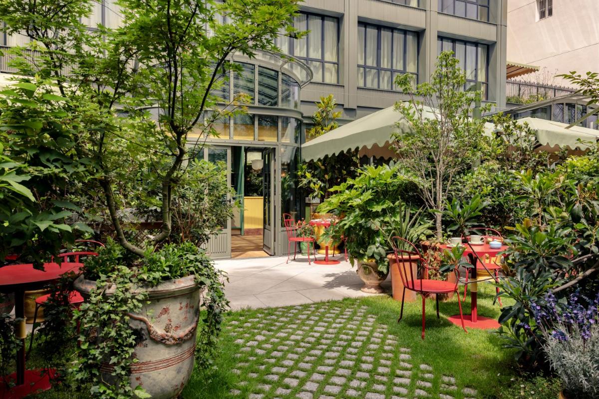 un jardin avec des tables et des chaises dans un bâtiment dans l'établissement La Fantaisie, à Paris