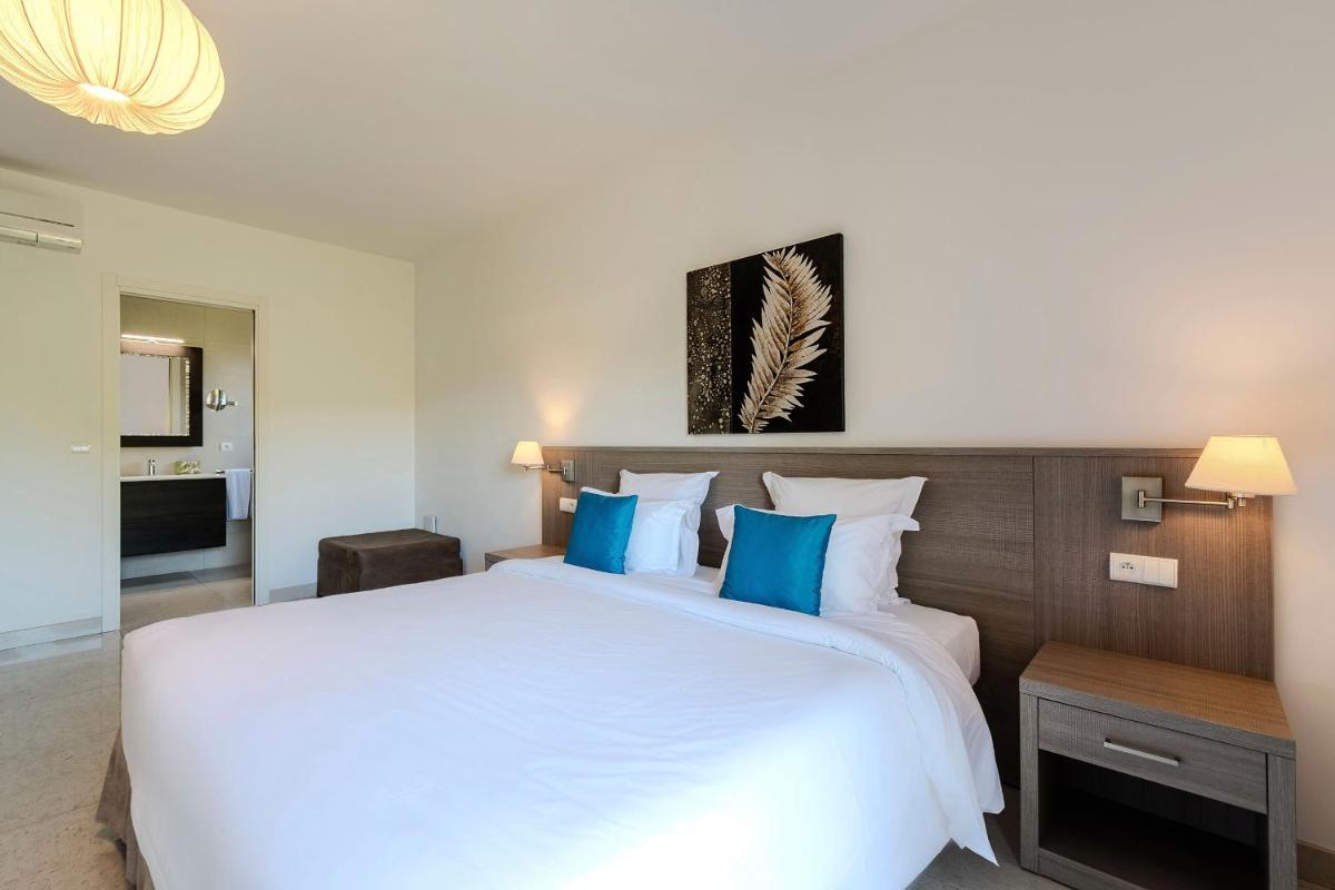 une chambre avec un grand lit blanc avec des oreillers bleus dans l'établissement Domaine Villas Mandarine Private Pools & Spa, à Calvi 37 autres photos