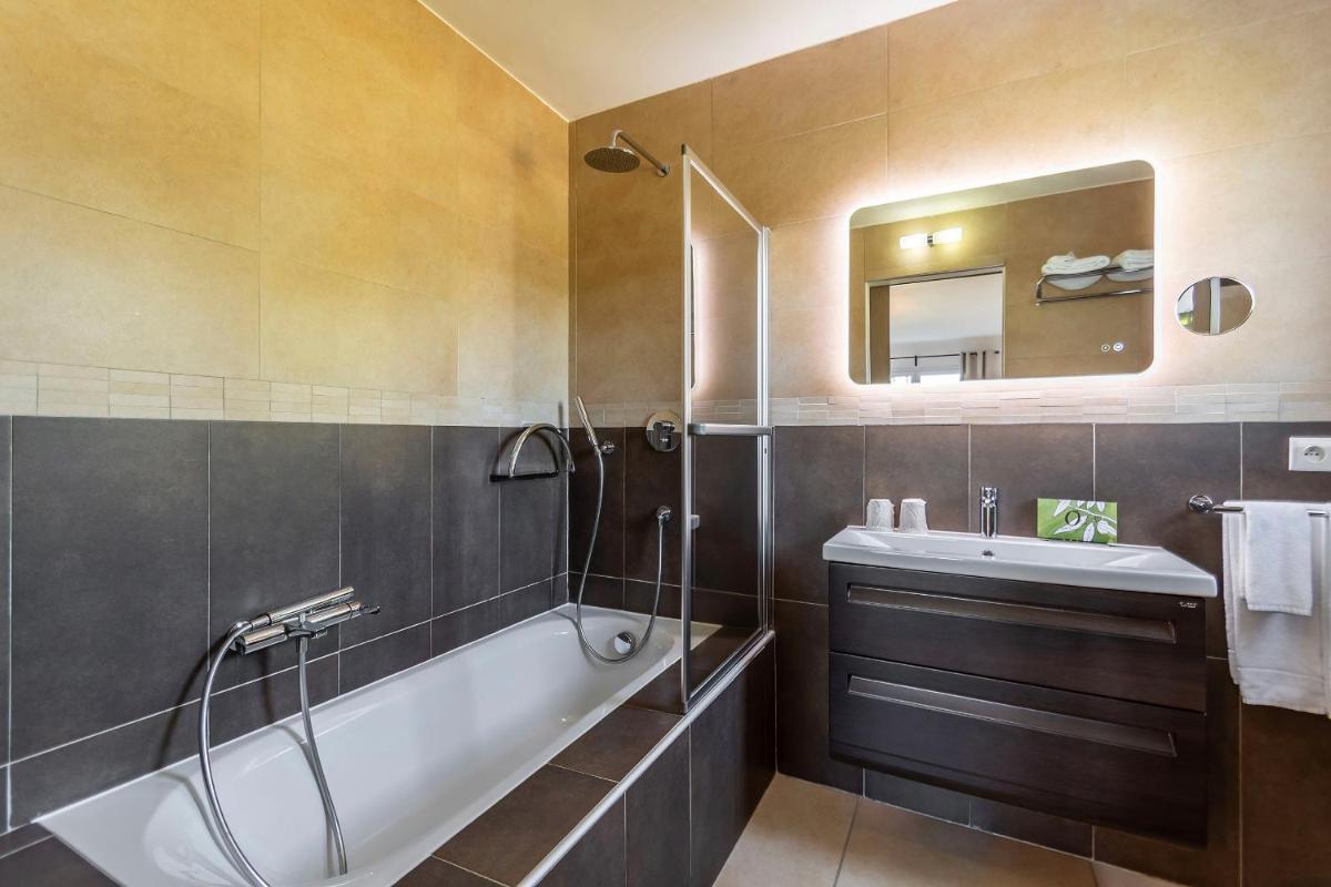 une salle de bain avec une baignoire, un lavabo et un miroir dans l'établissement Domaine Villas Mandarine Private Pools & Spa, à Calvi