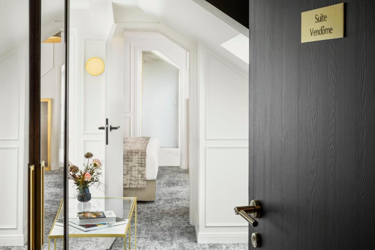 un couloir avec une porte et une table en verre dans l'établissement Maison Albar - Le Vendome, à Paris