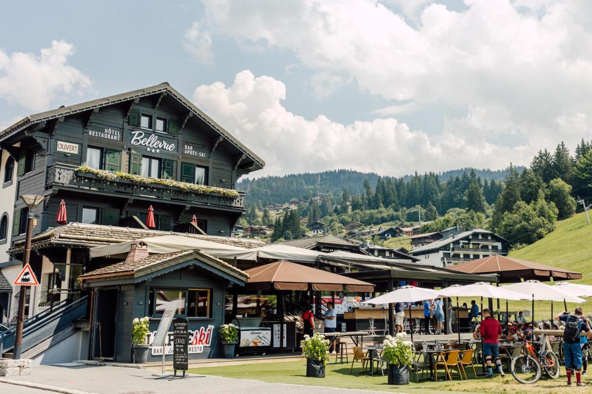 un bâtiment avec des tables et des parasols devant lui dans l'établissement Bellevue, aux Gets
