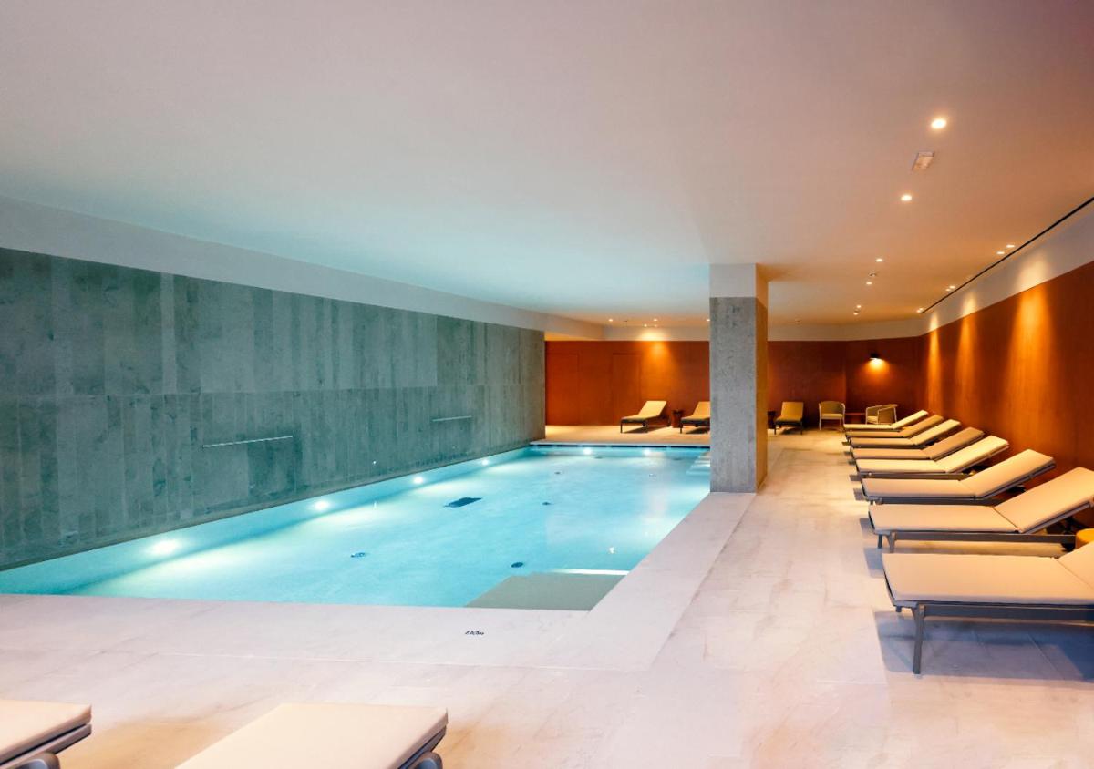 uma grande piscina com espreguiçadeiras num edifício em Montebelo Viseu Congress Hotel & Spa em Viseu