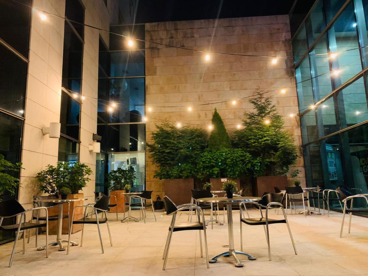 Un restaurante con mesas y sillas frente a un edificio. en Hotel Torresport, en Torrelavega