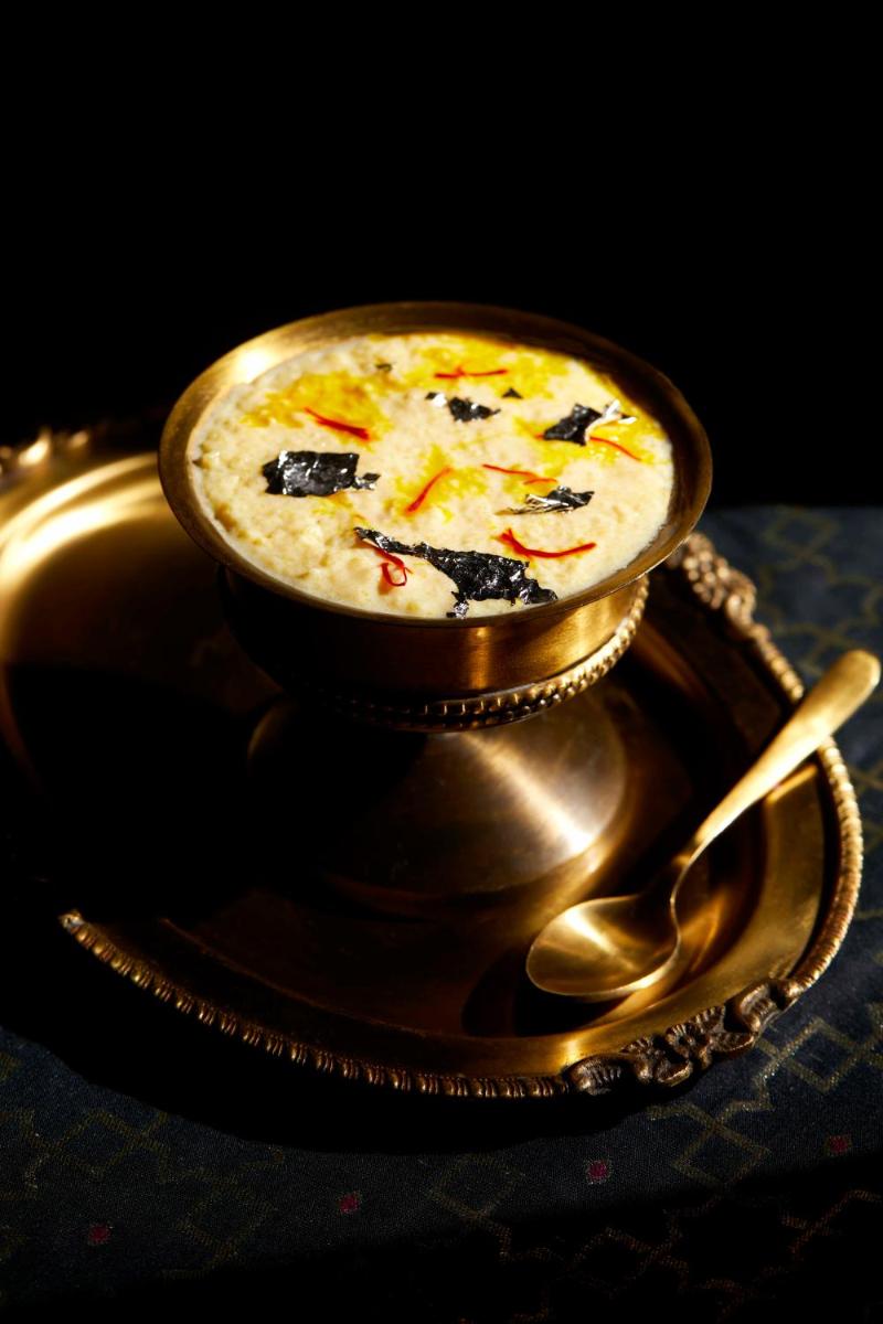a gold bowl of soup with a spoon on a table at JW Marriott Mumbai Juhu in Mumbai