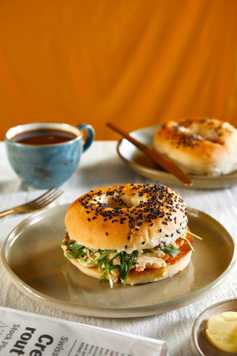 a plate with a bagel sandwich and a cup of coffee at JW Marriott Mumbai Juhu in Mumbai