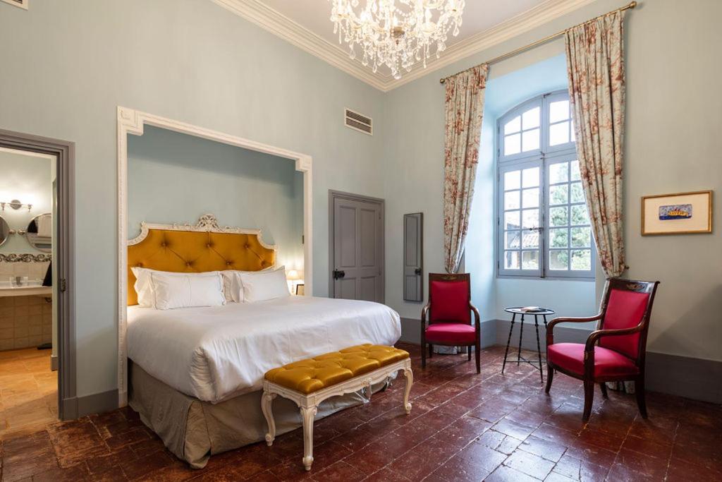 - une chambre avec un grand lit et deux chaises rouges dans l'établissement Château de Collias, à Collias