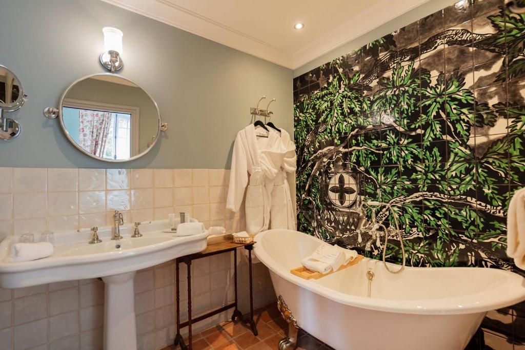 une salle de bain avec une baignoire, un lavabo et un miroir dans l'établissement Château de Collias, à Collias