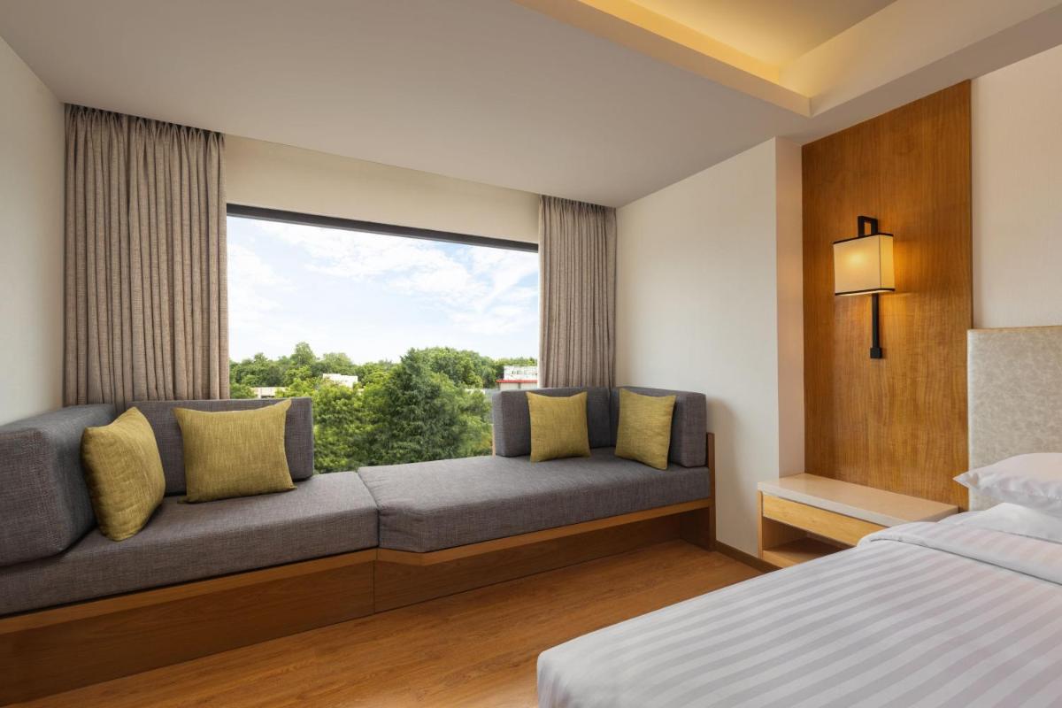 a bedroom with a couch with a large window at Courtyard by Marriott Tiruchirappalli in Tiruchchirāppalli