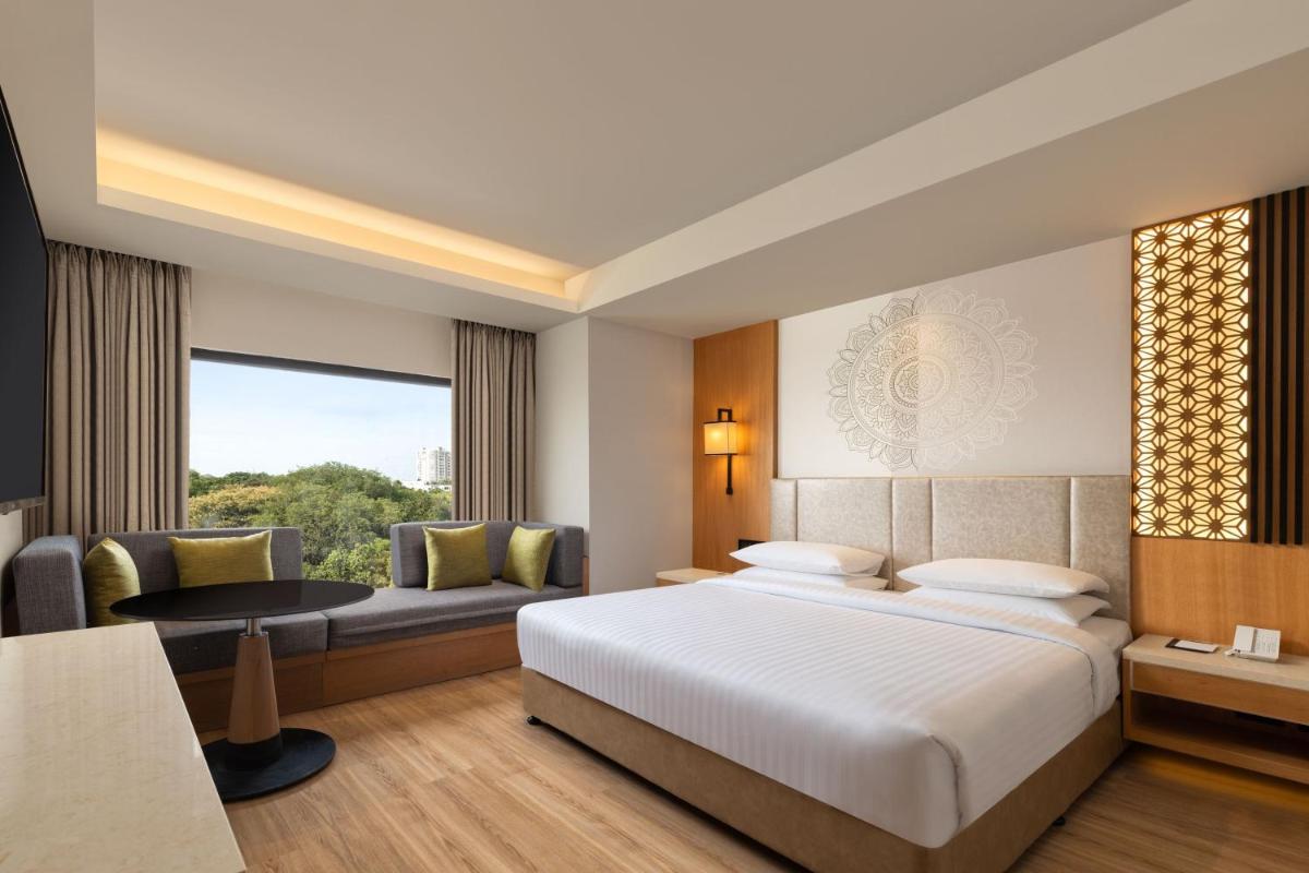 a hotel room with a bed and a couch at Courtyard by Marriott Tiruchirappalli in Tiruchchirāppalli