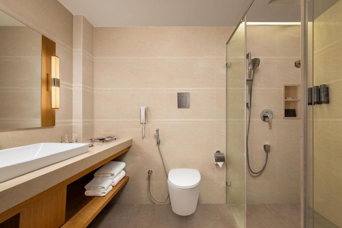 a bathroom with a shower and a toilet and a sink at Courtyard by Marriott Tiruchirappalli in Tiruchchirāppalli