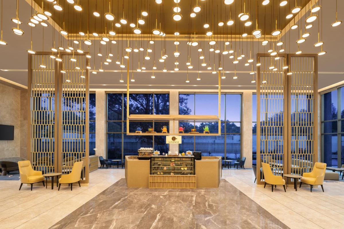a lobby with a bar and chairs and lights at Courtyard by Marriott Tiruchirappalli in Tiruchchirāppalli