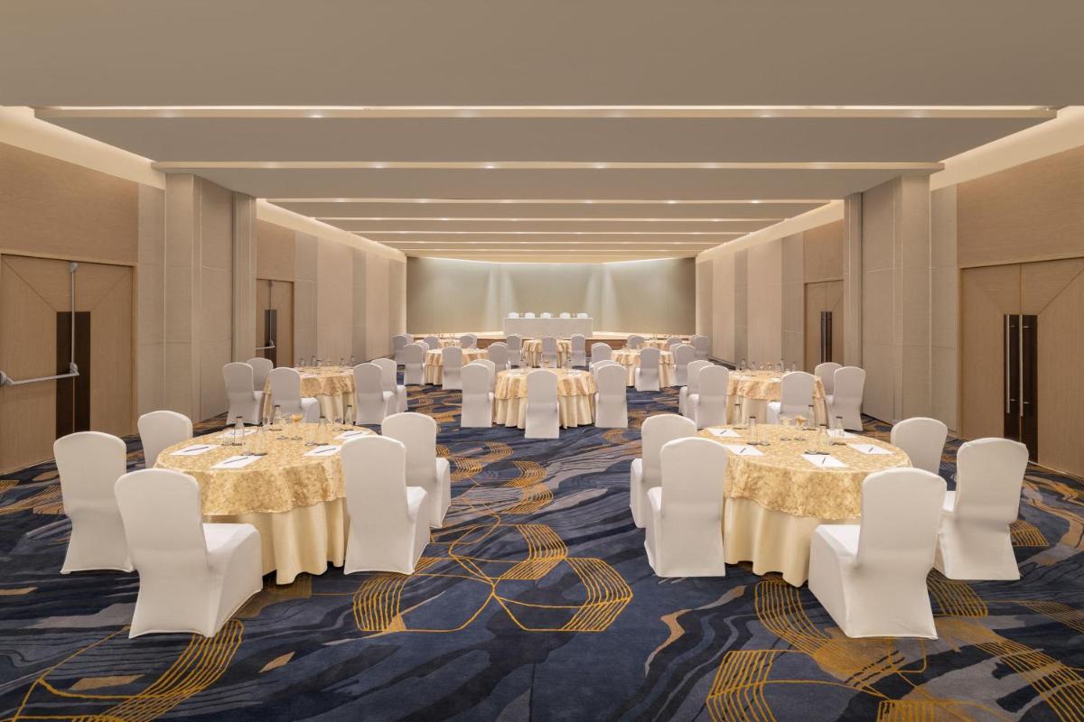 a banquet hall with tables and white chairs at Courtyard by Marriott Tiruchirappalli in Tiruchchirāppalli