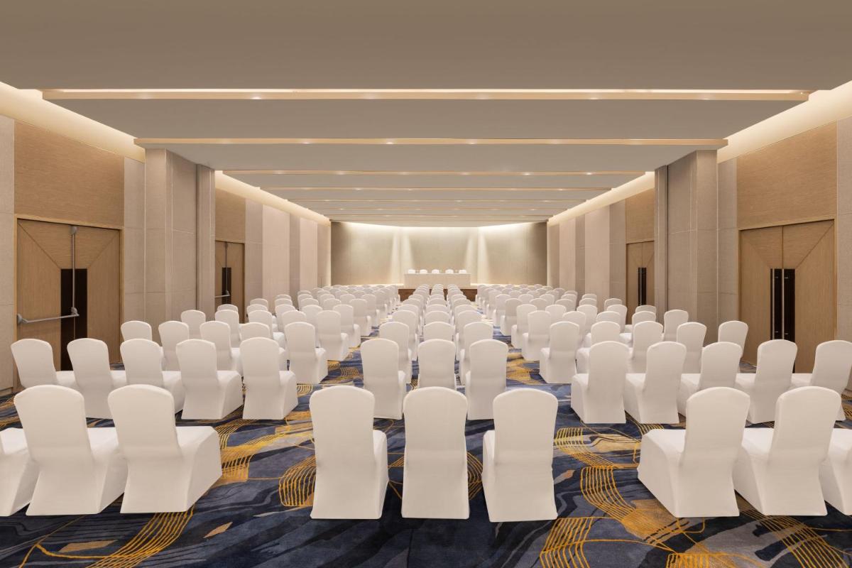 a conference room with white chairs and tables at Courtyard by Marriott Tiruchirappalli in Tiruchchirāppalli