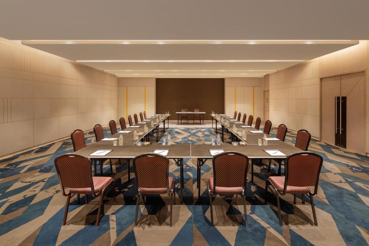 a large conference room with long tables and chairs at Courtyard by Marriott Tiruchirappalli in Tiruchchirāppalli