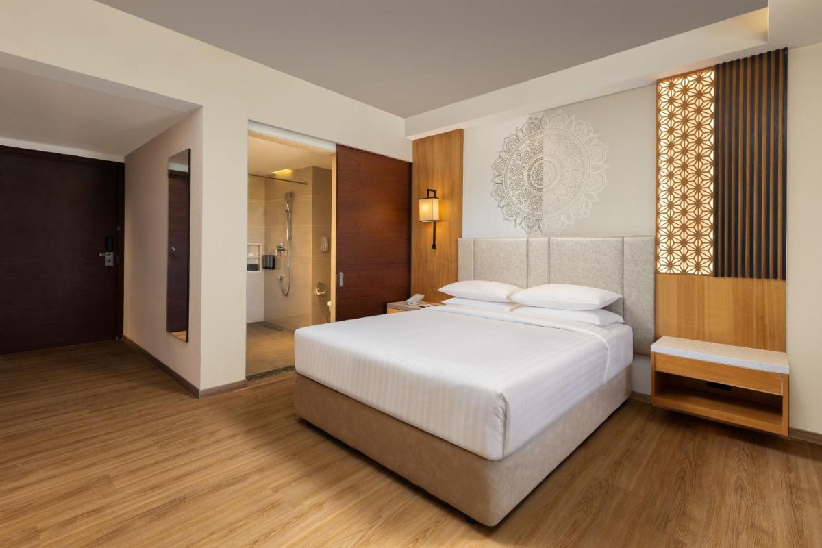 a bedroom with a large white bed and a bathroom at Courtyard by Marriott Tiruchirappalli in Tiruchchirāppalli