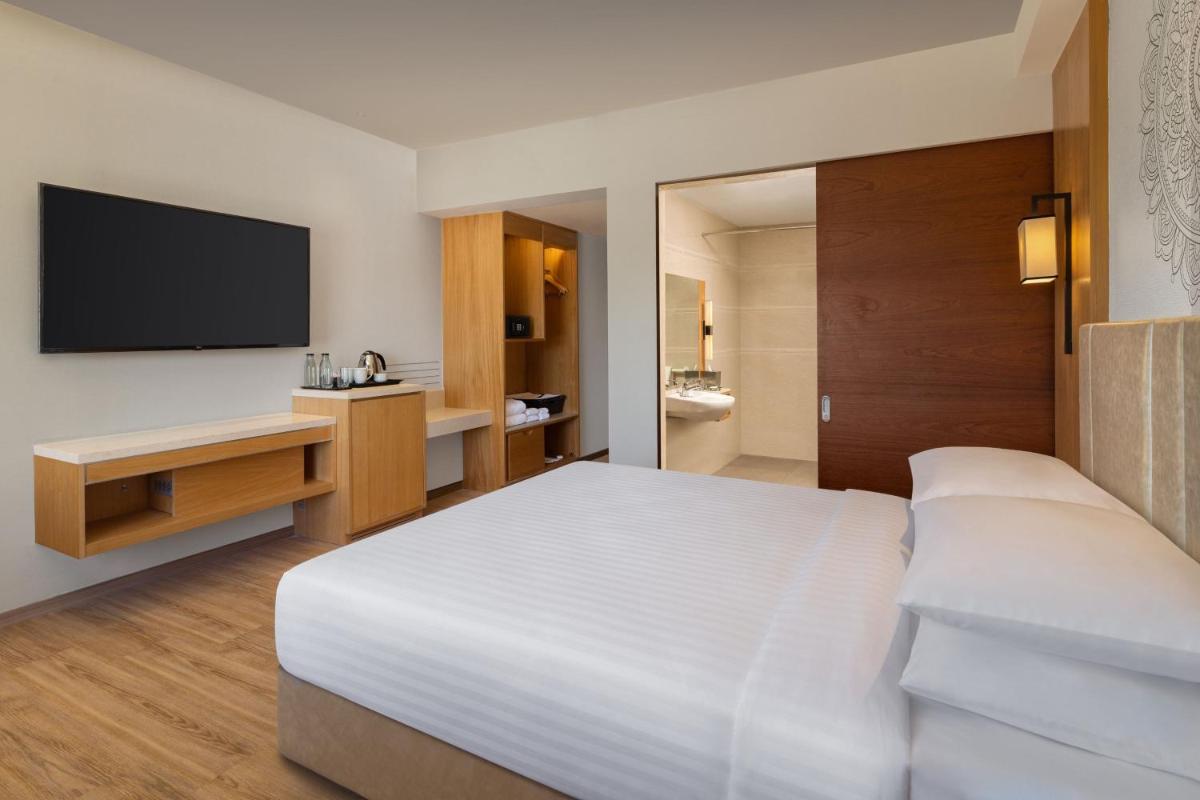 a hotel room with a bed and a television at Courtyard by Marriott Tiruchirappalli in Tiruchchirāppalli